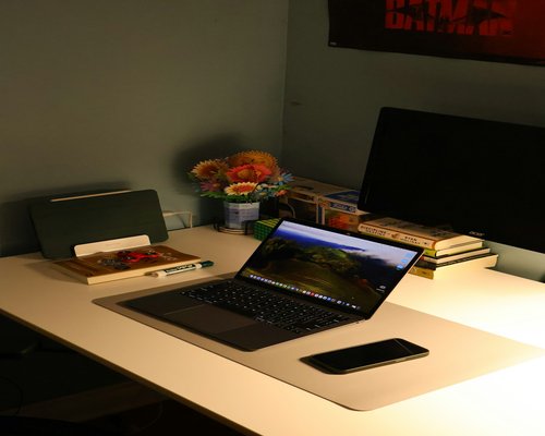 Close-up of a well-organized desk layout featuring warm diffused backing lights and comfortable monitor contrast settings.