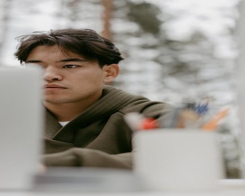 A close-up shot of a person relaxing their gaze by looking outside towards a green scenery during a study break.
